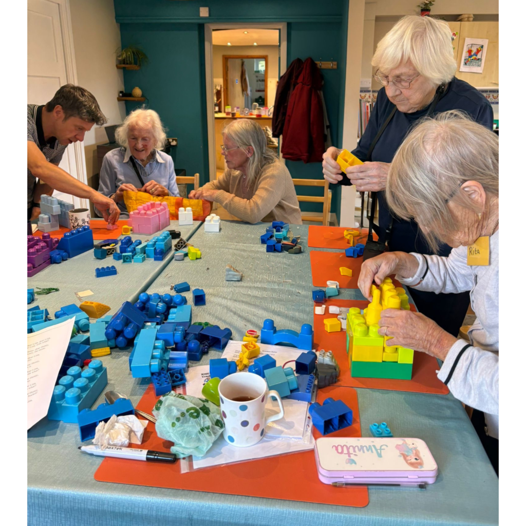 Group of seniors at a table building with colorful LEGO bricks and craft supplies.
